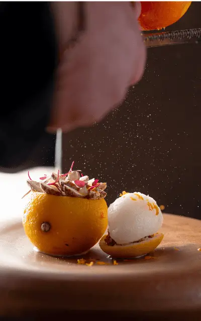 http://A%20person%20skillfully%20carves%20the%20top%20of%20a%20vibrant%20orange%20on%20a%20wooden%20surface.%20Shavings%20and%20zest%20scatter,%20conveying%20a%20sense%20of%20freshness%20and%20artistry.