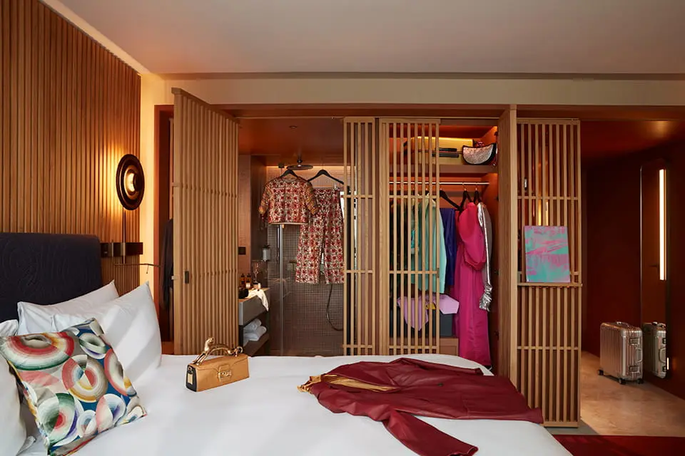 http://Interior%20of%20a%20bedroom%20with%20open%20wardrobe%20and%20white%20sheets%20on%20bed.