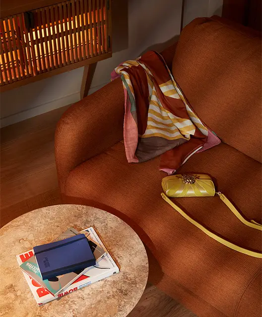 Yellow handbag and colourful scarf on a burnt orange coloured sofa