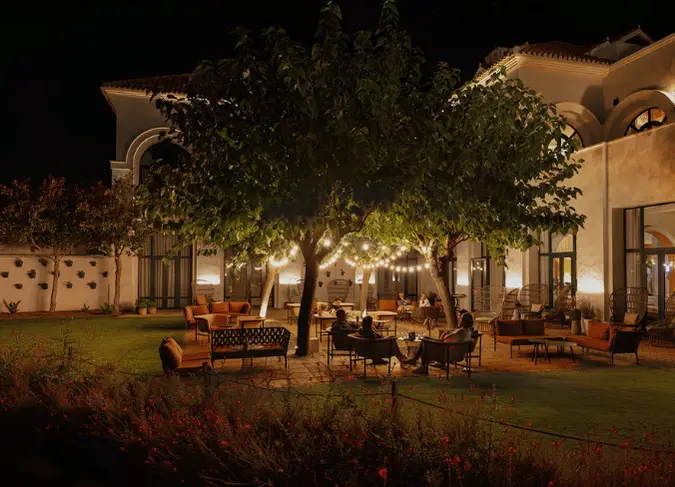 http://A%20nighttime%20patio%20scene%20illuminated%20by%20soft%20lights,%20showcasing%20outdoor%20furniture%20and%20a%20cozy%20atmosphere.