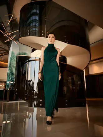 http://A%20woman%20in%20an%20elegant%20green%20dress%20stands%20confidently%20in%20a%20modern%20interior%20with%20a%20spiral%20staircase%20behind%20her,%20conveying%20sophistication%20and%20grace.