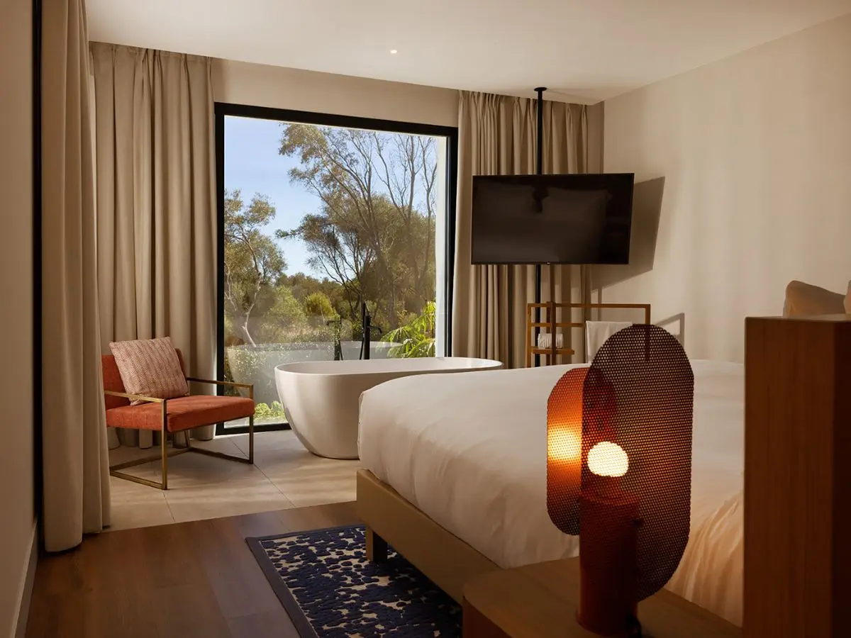A spacious hotel room featuring a large bed and a stylish bathtub, creating a comfortable and relaxing atmosphere.