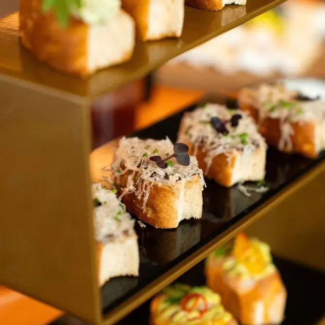 Close-up of a tiered appetizer stand featuring gourmet small bites and cheese toasts.