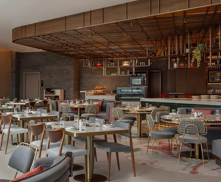 http://Dining%20room%20at%20restaurant%20with%20multiple%20square%20and%20round%20tables%20and%20comfortable%20seats