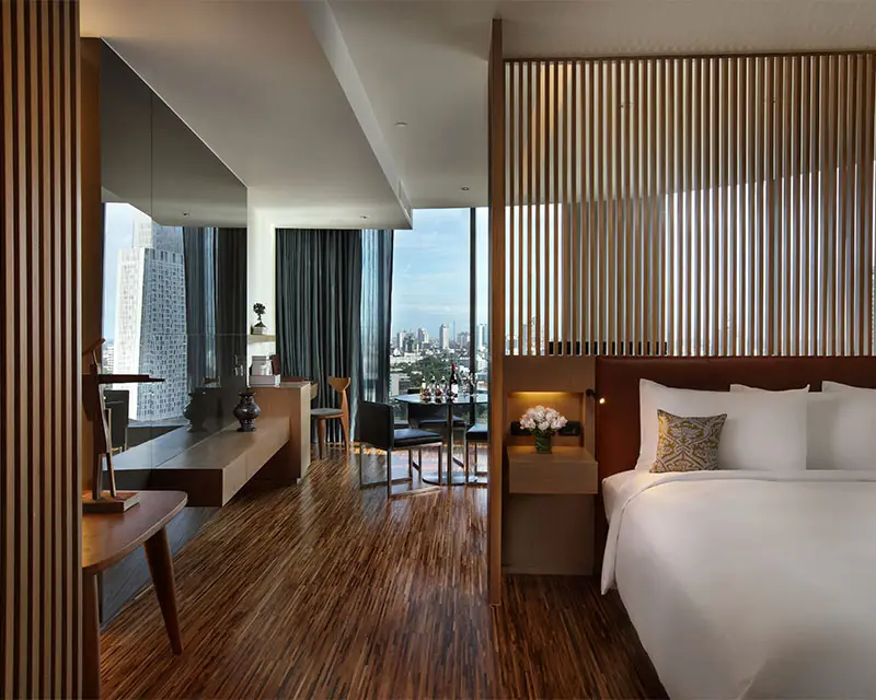 http://A%20large%20wooden-themed%20hotel%20room%20with%20a%20double%20bed.%20Daylight%20floods%20the%20room%20from%20the%20floor%20to%20ceiling%20windows.