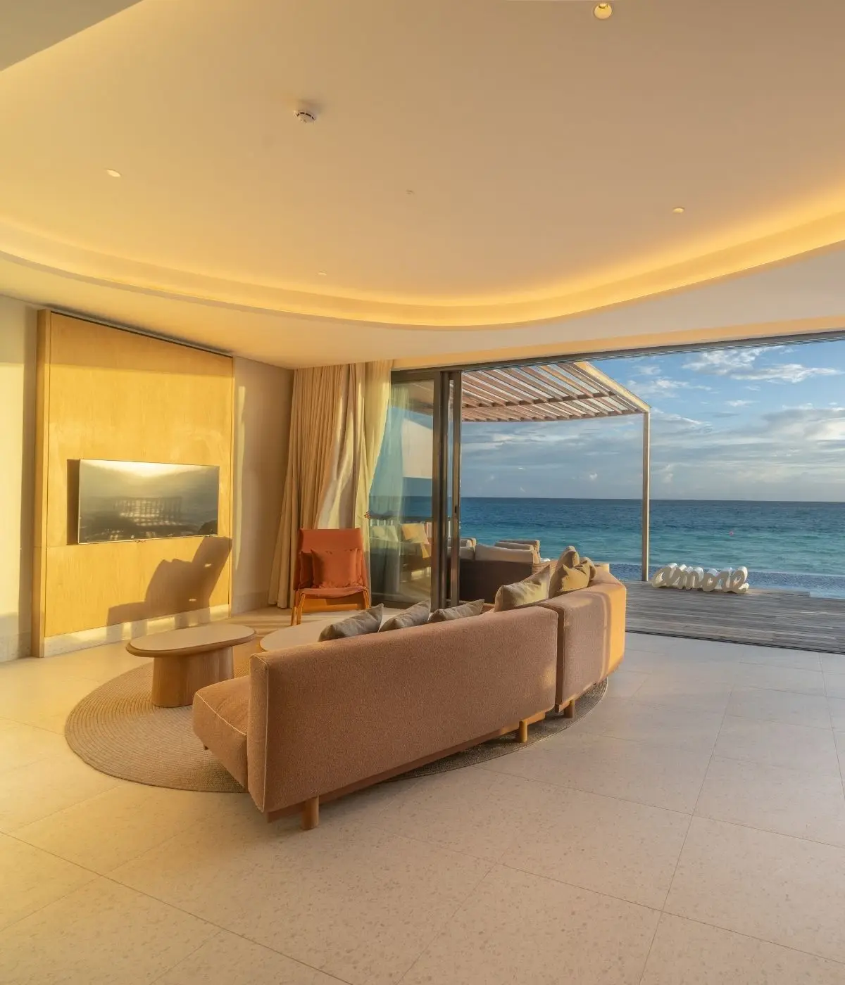 A cozy beachfront living area with a large window overlooking the ocean, featuring modern furniture and natural light.