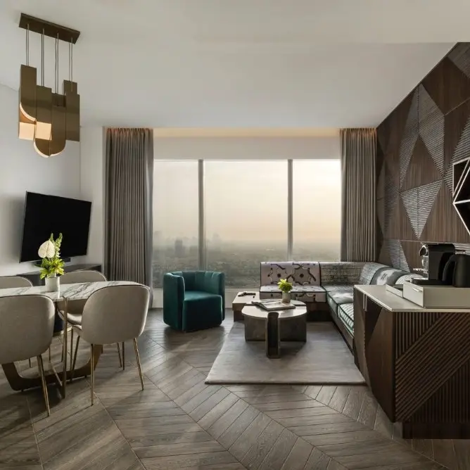 Luxurious modern hotel room with large windows offering a city view. Features a plush bed, stylish lamps, and cozy seating, creating a serene ambiance.